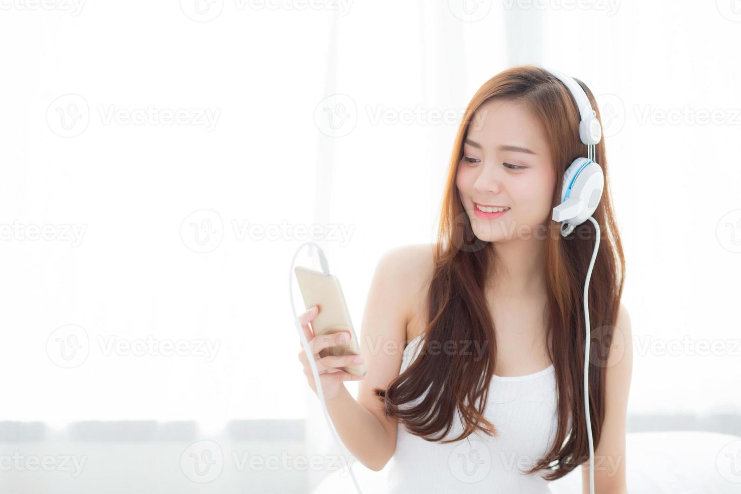 Mujer asiática disfruta de escuchar música con auriculares y sosteniendo un teléfono inteligente foto