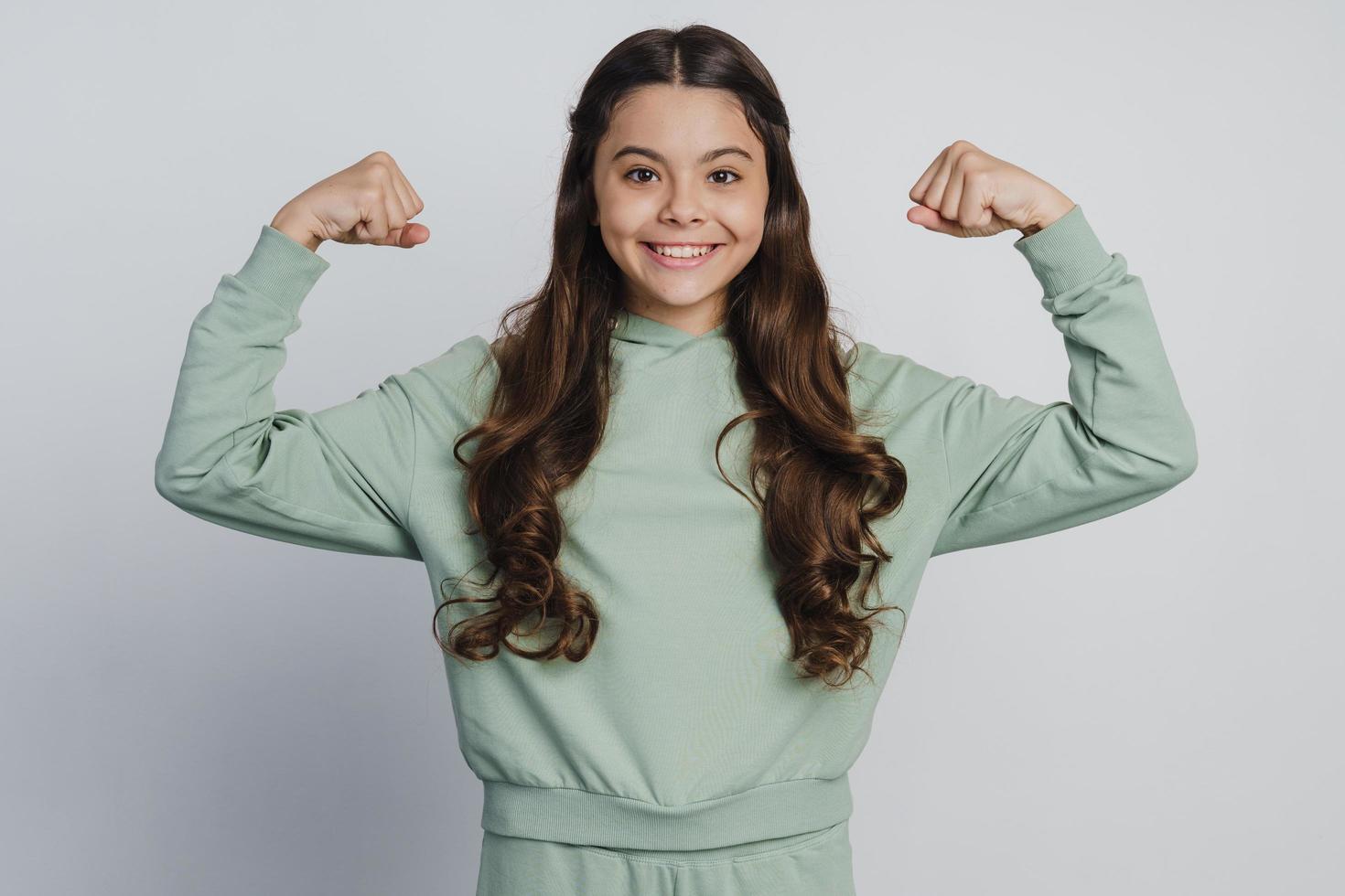 niña sonriente muestra bíceps. la niña levantó las manos foto