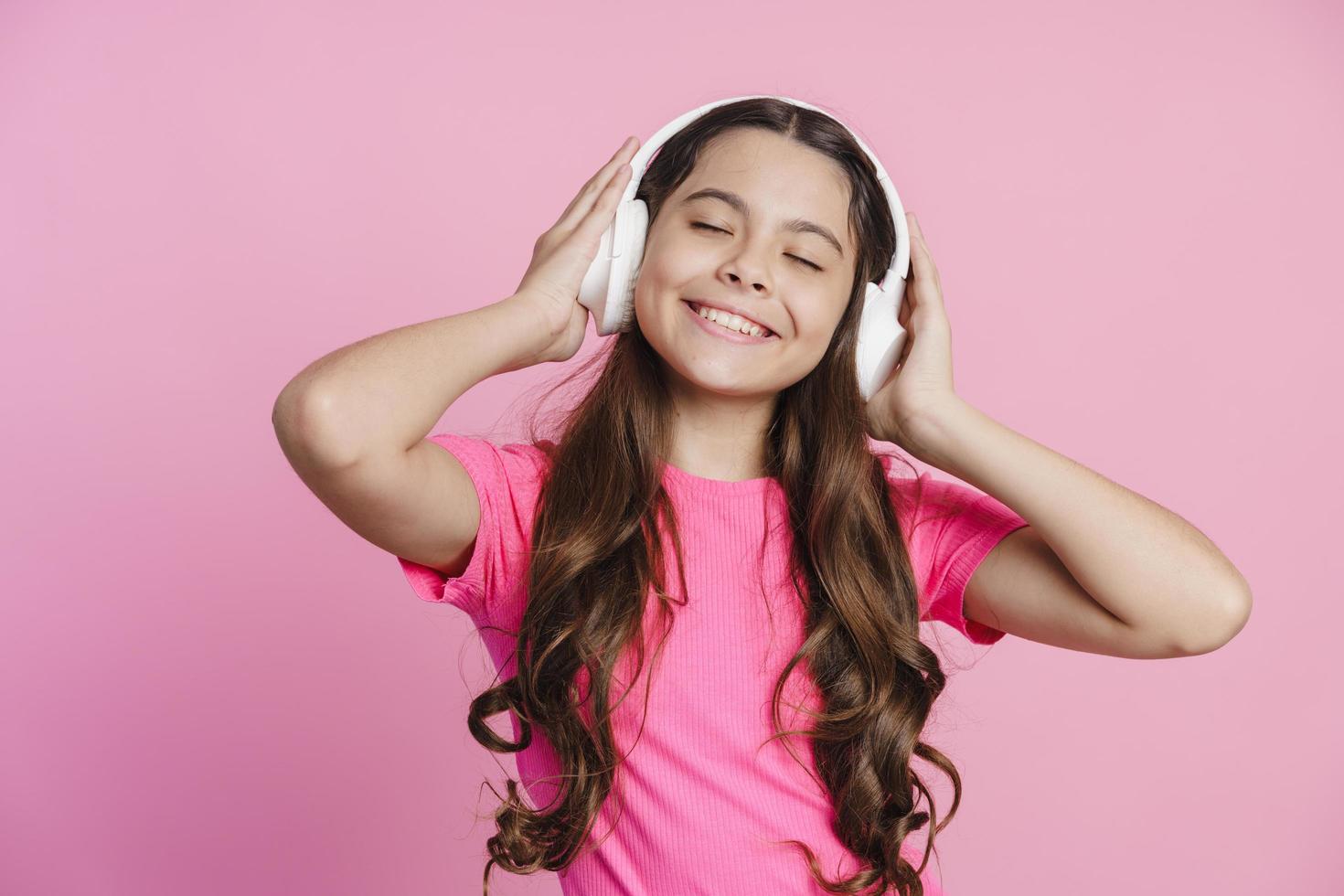 Atractiva adolescente en auriculares inalámbricos escucha música foto