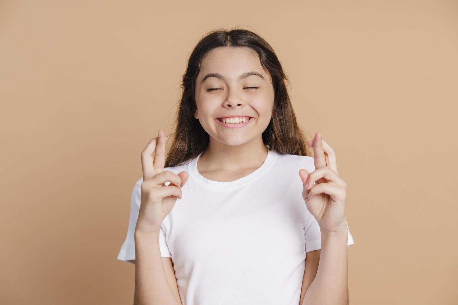 Funny, cute teenage girl crossed her fingers, closed her eyes photo