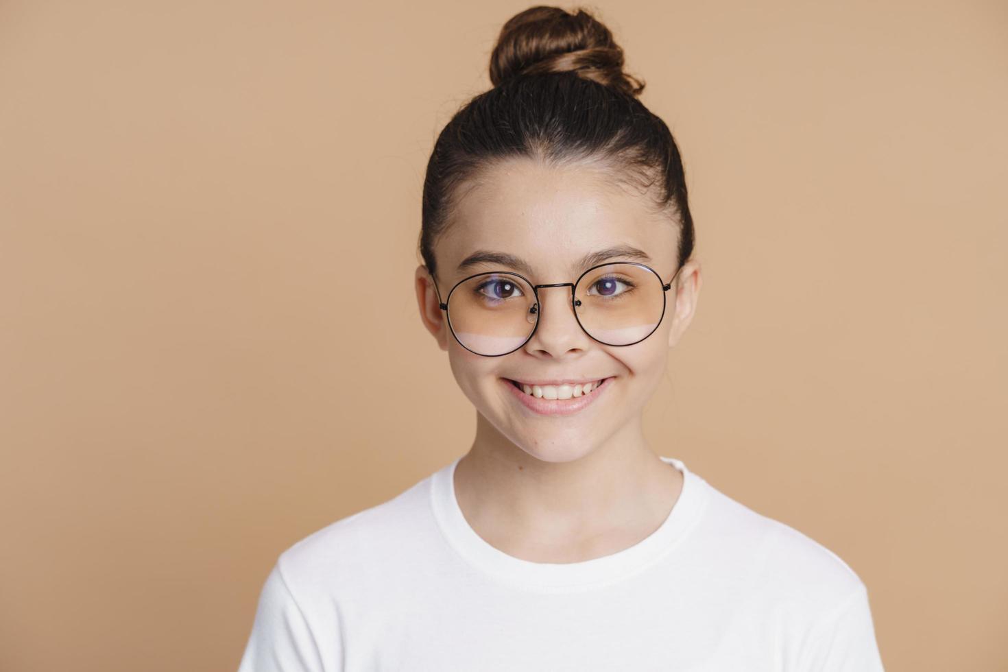 Beautiful, attractive little girl on a brown background with glasses photo