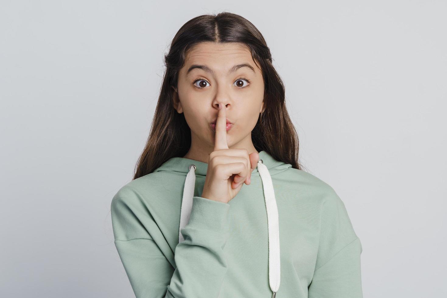 Curious, beautiful teenage girl shows gesture to be quiet photo