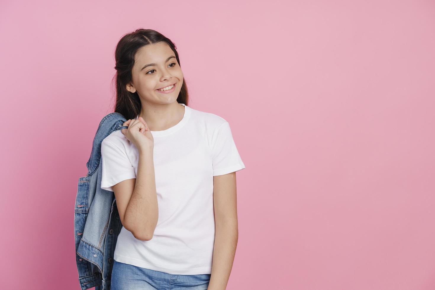 Hermosa adolescente sosteniendo una chaqueta de mezclilla sobre sus hombros foto