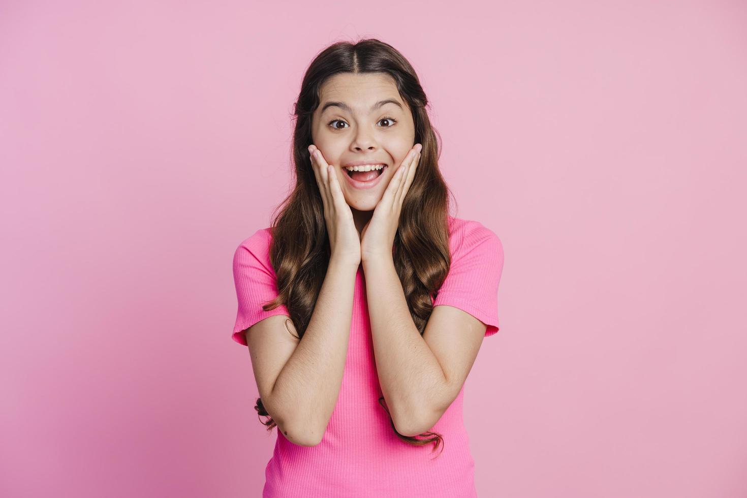 Surprised teenage girl touches her face with her hands photo