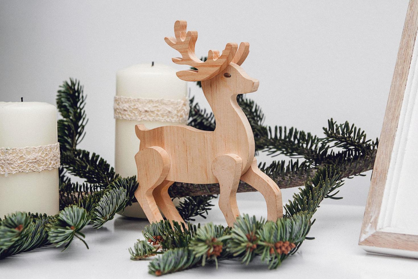Tres velas navideñas, rama de pino y ciervo de madera. foto