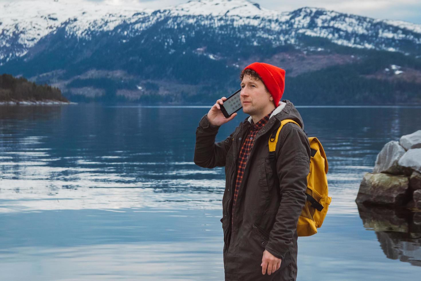 Traveler man talking on mobile phone against of the mountain photo