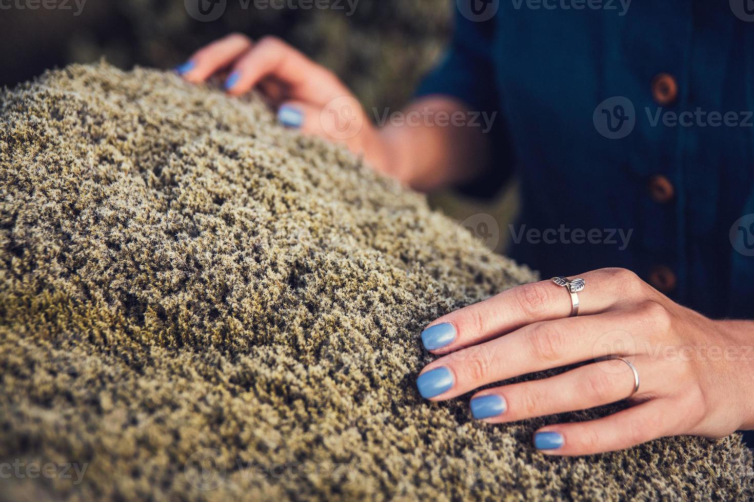 Woman touching the stone moss in nature and exchanging emotion energy photo