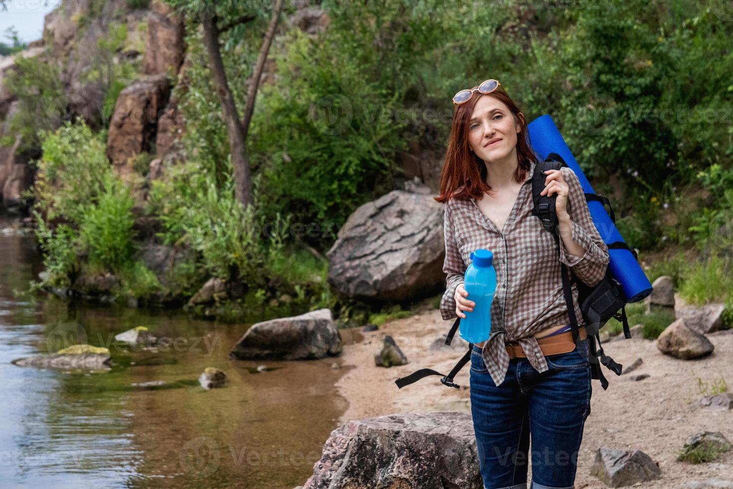 mujer turista con una mochila un fondo de montañas y ríos foto