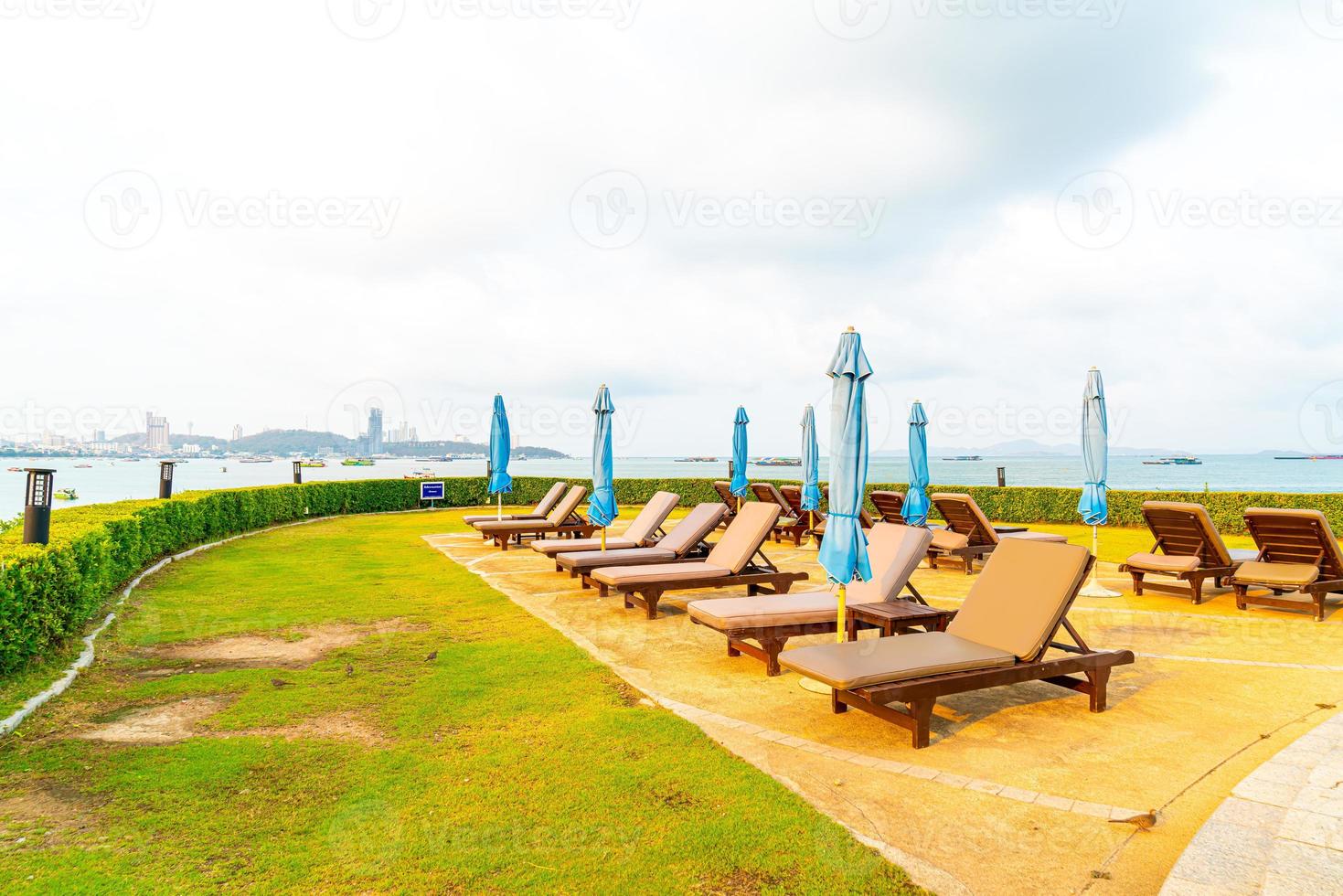 Chair pool or bed pool and umbrella around swimming pool with sea beach background at Pattaya in Thailand photo