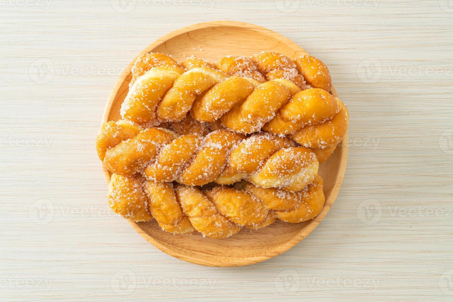 Sugar doughnut in a spiral shape on wooden plate photo