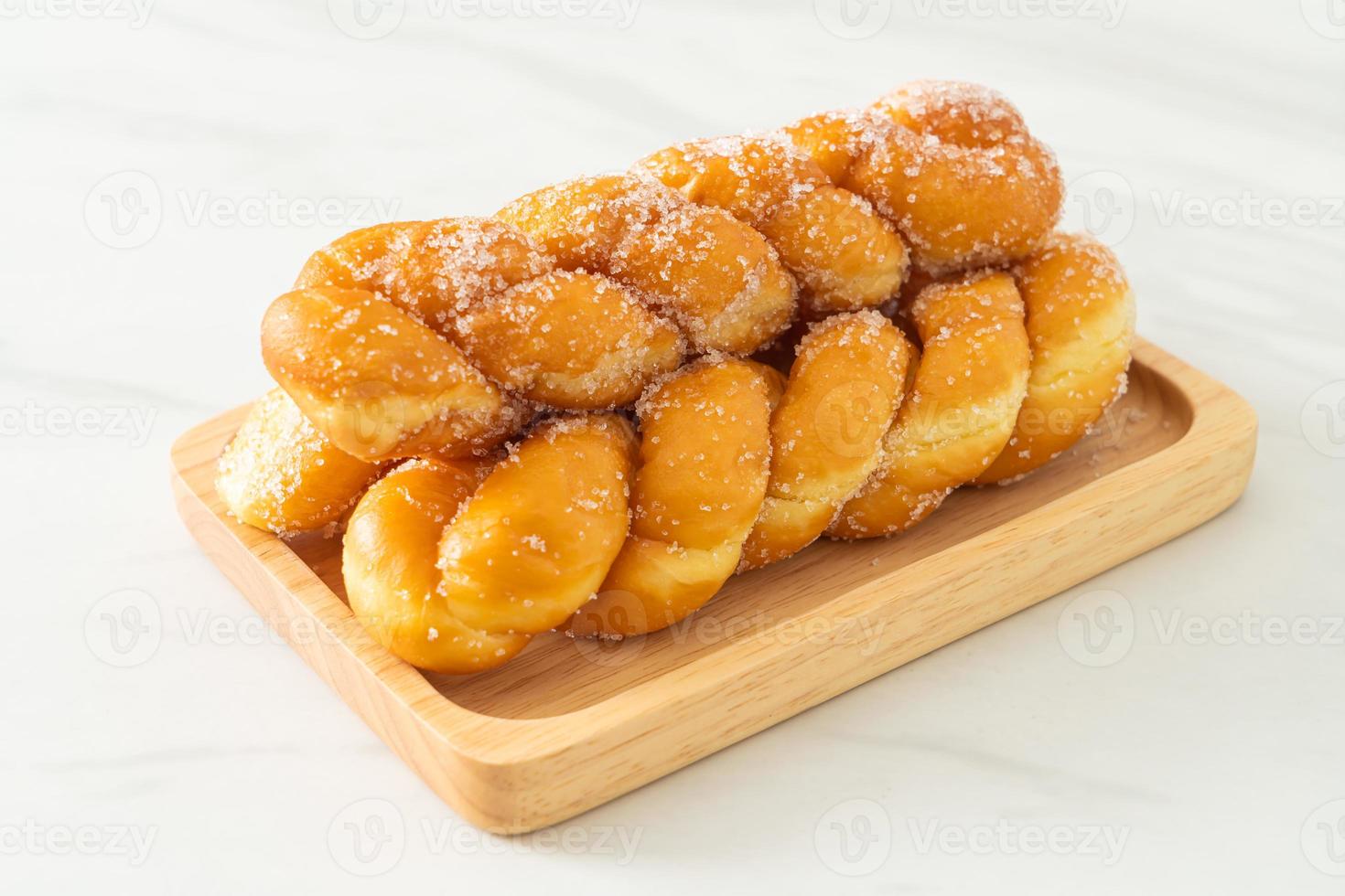 Sugar doughnut in a spiral shape on wooden plate photo