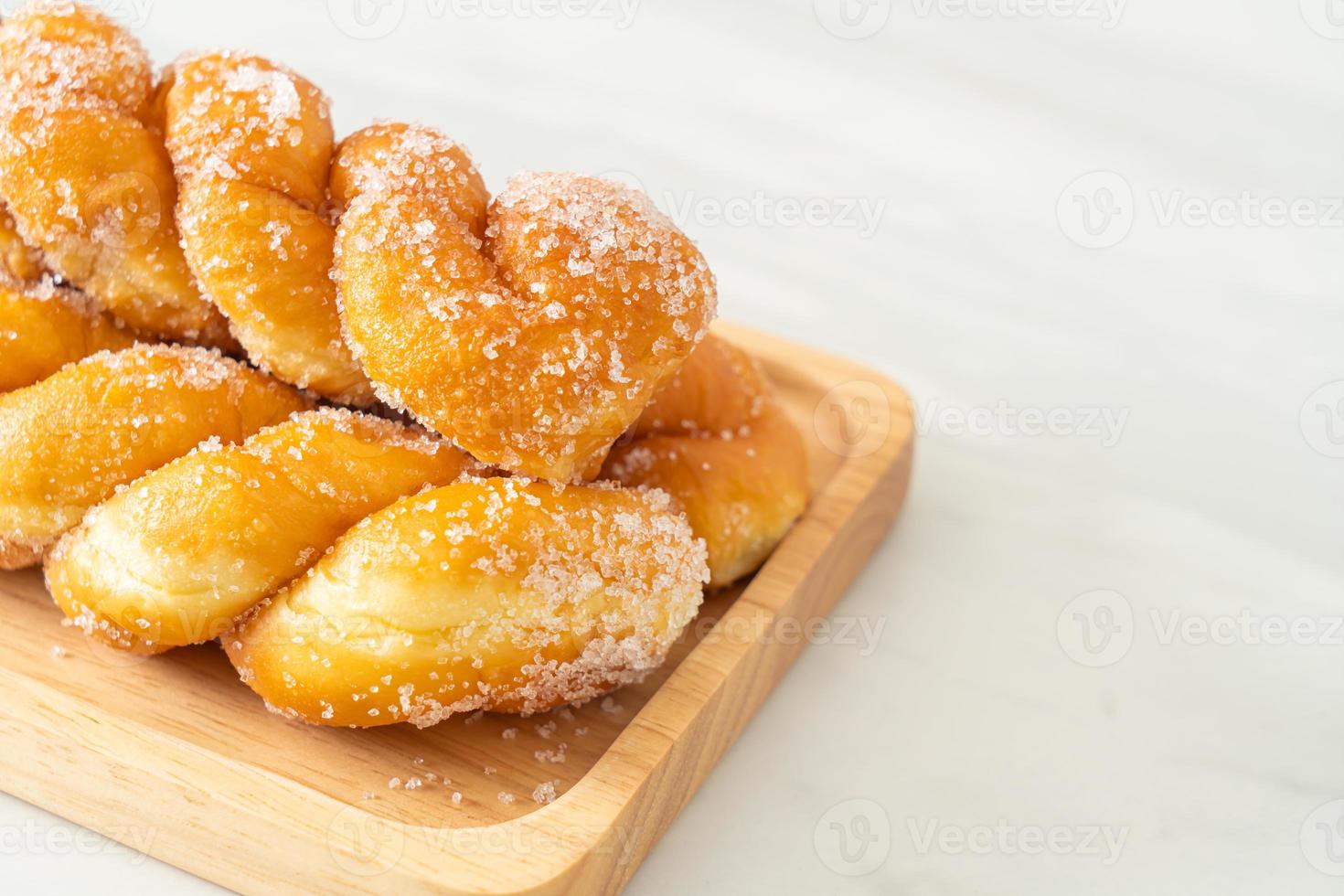 Sugar doughnut in a spiral shape on wooden plate photo