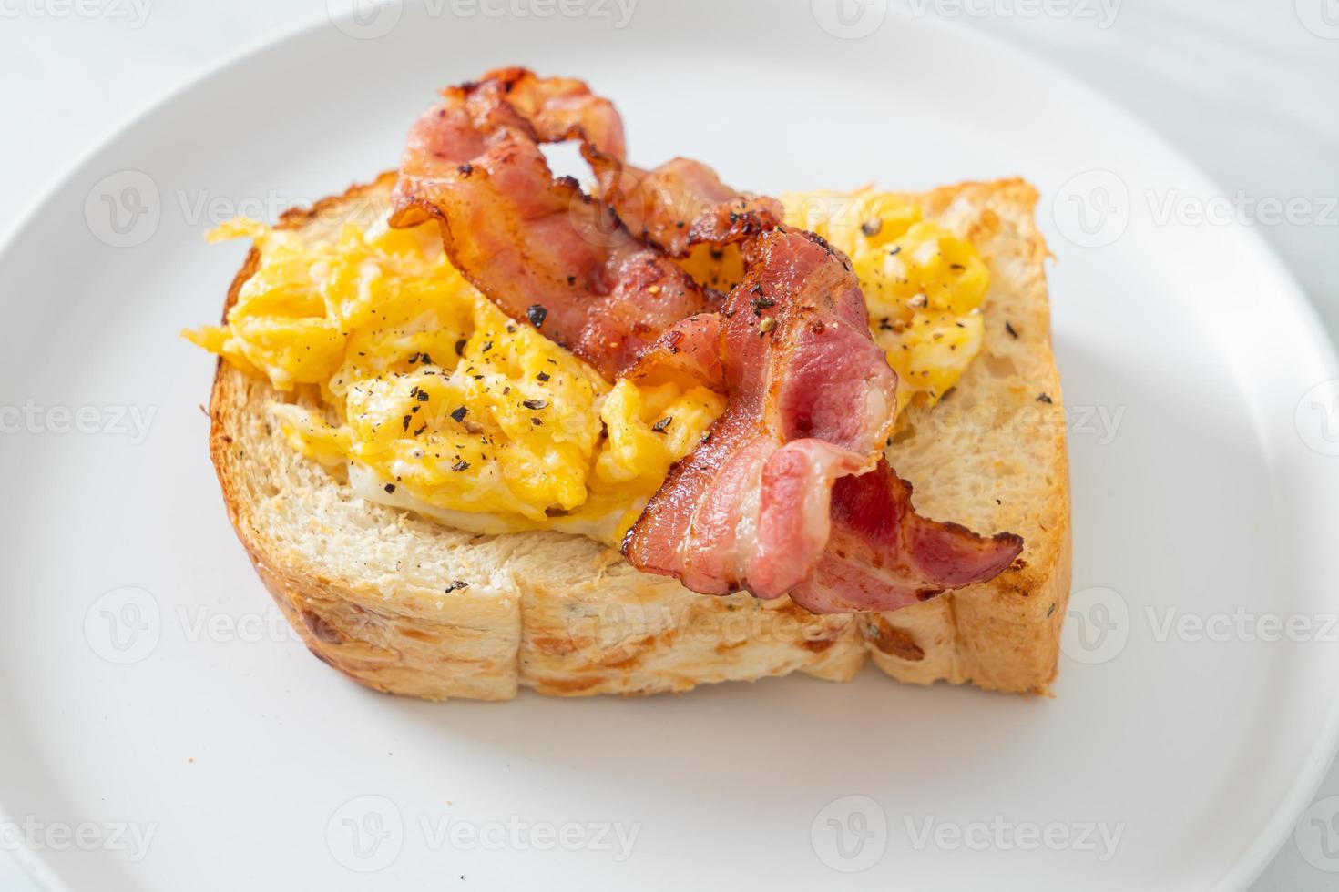 Bread toast with scramble egg and bacon on white plate photo