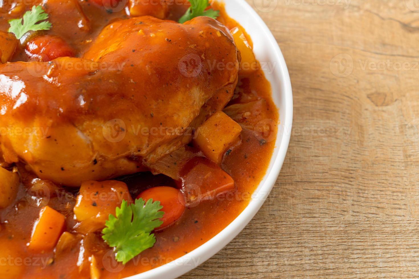 Homemade chicken stew with tomatoes, onions, carrot, and potatoes on plate photo