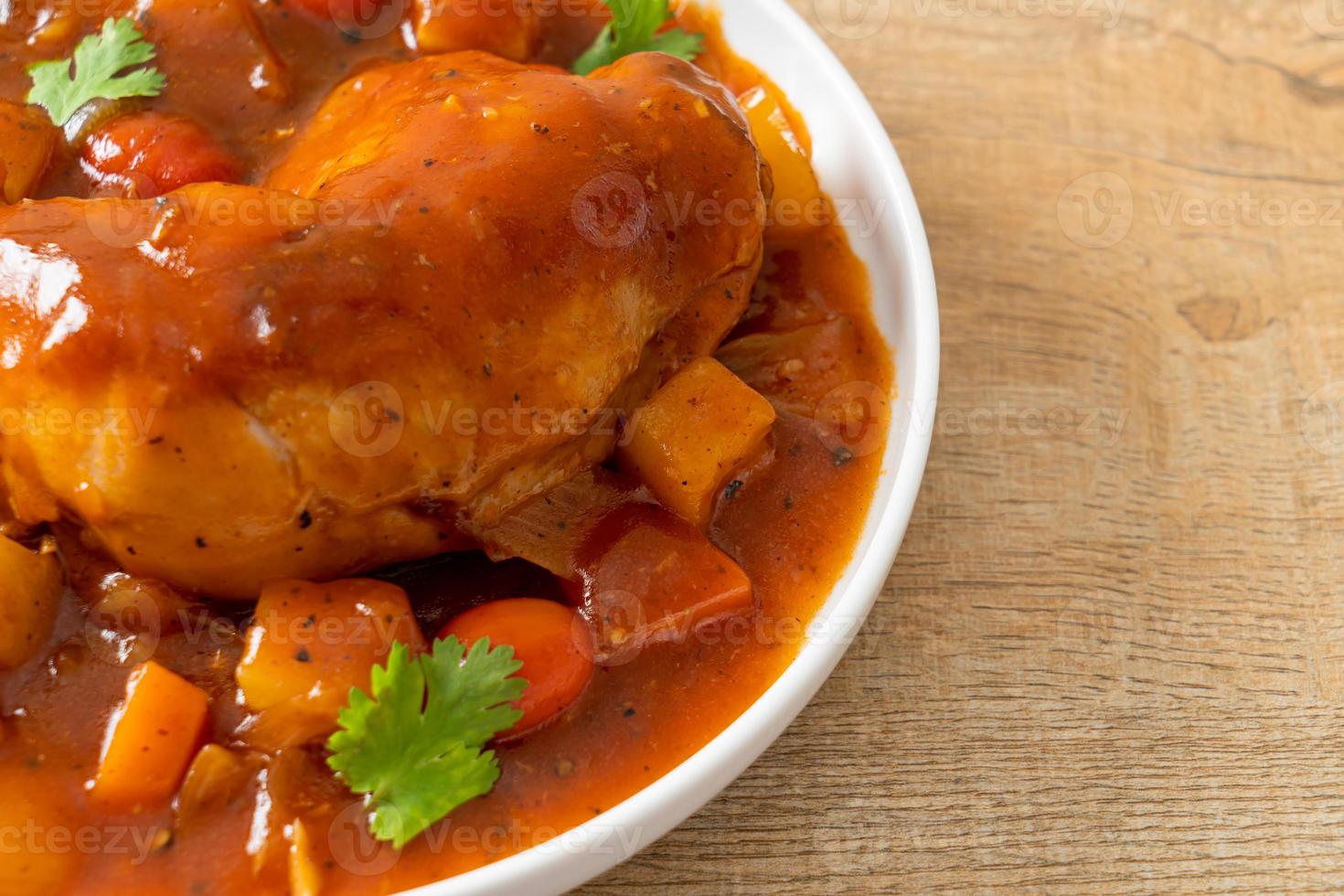 Estofado de pollo casero con tomates, cebollas, zanahorias y patatas en un plato foto