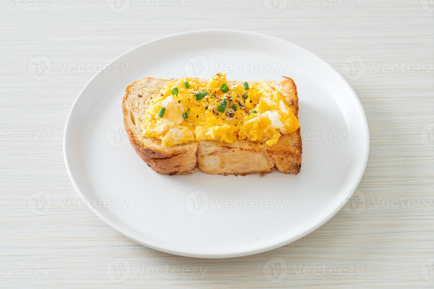 Tostadas de pan con huevos revueltos en la placa blanca. foto
