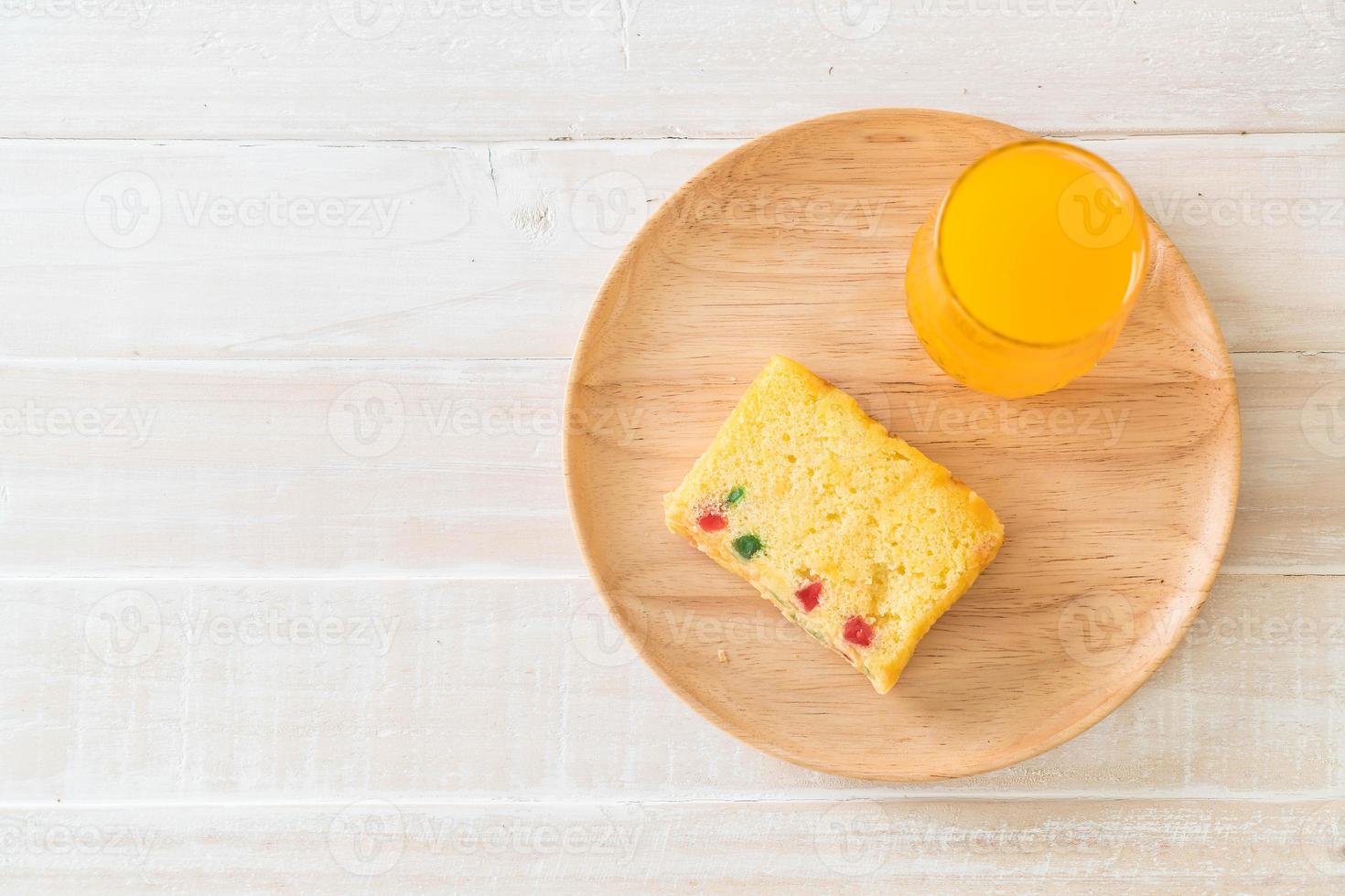 Pastel de frutas en placa de madera con jugo de naranja foto