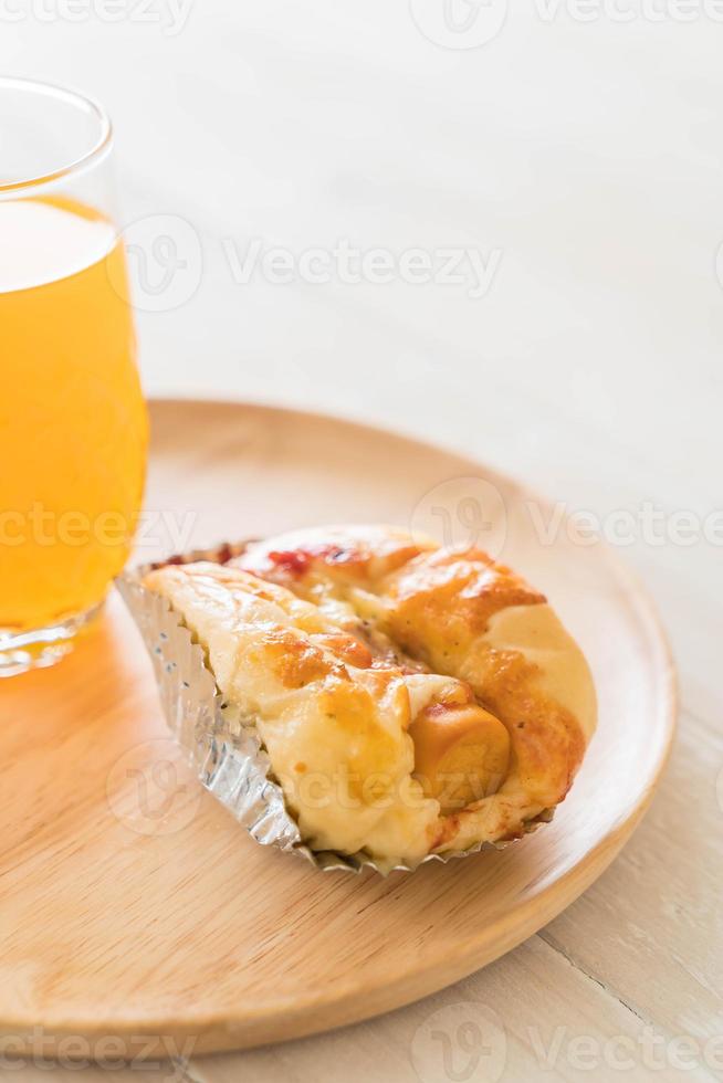 Pan de mayonesa de salchicha con jugo de naranja sobre placa de madera foto