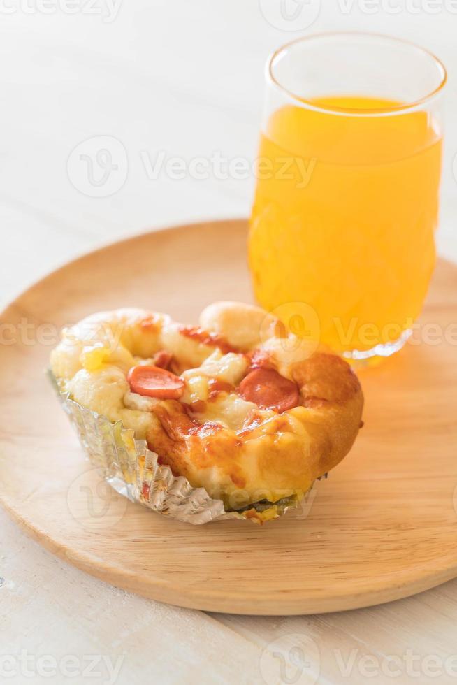 Pan de mayonesa de salchicha con jugo de naranja sobre placa de madera foto