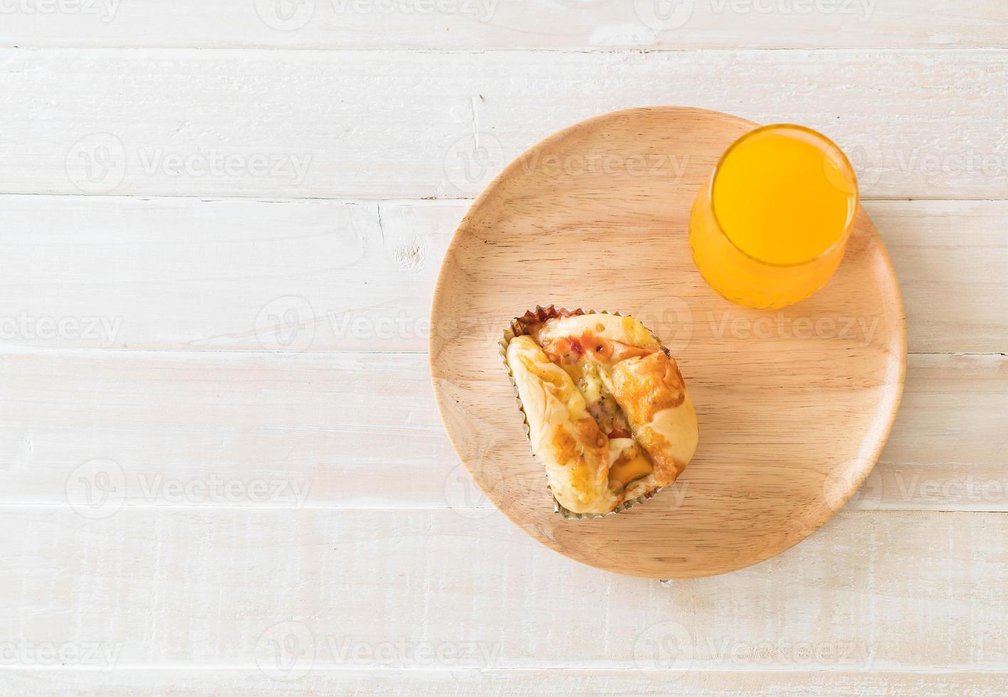 Pan de mayonesa de salchicha con jugo de naranja sobre placa de madera foto