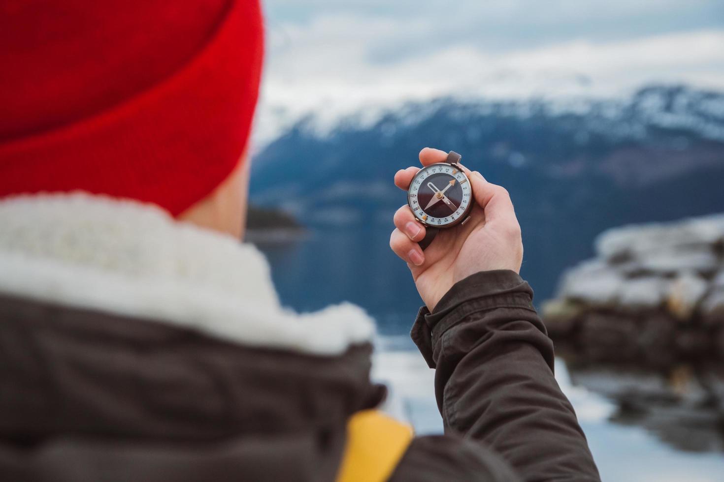 Traveler man holds an old compass against of the mountain and a lake photo