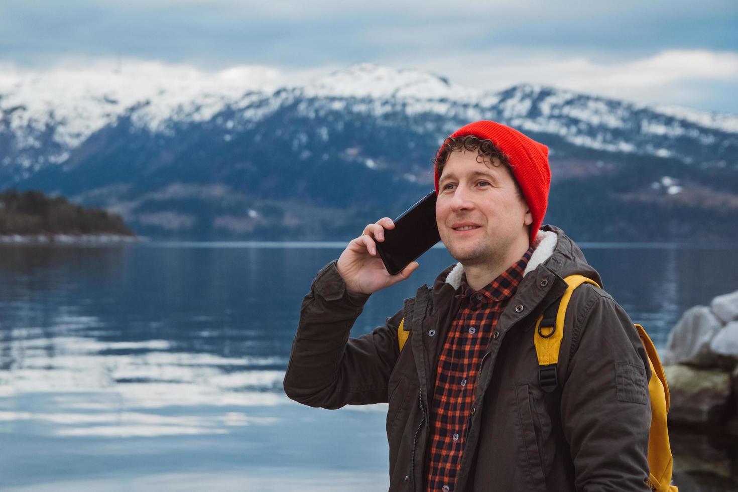 Portrait traveler man talking on mobile phone against of the mountain photo