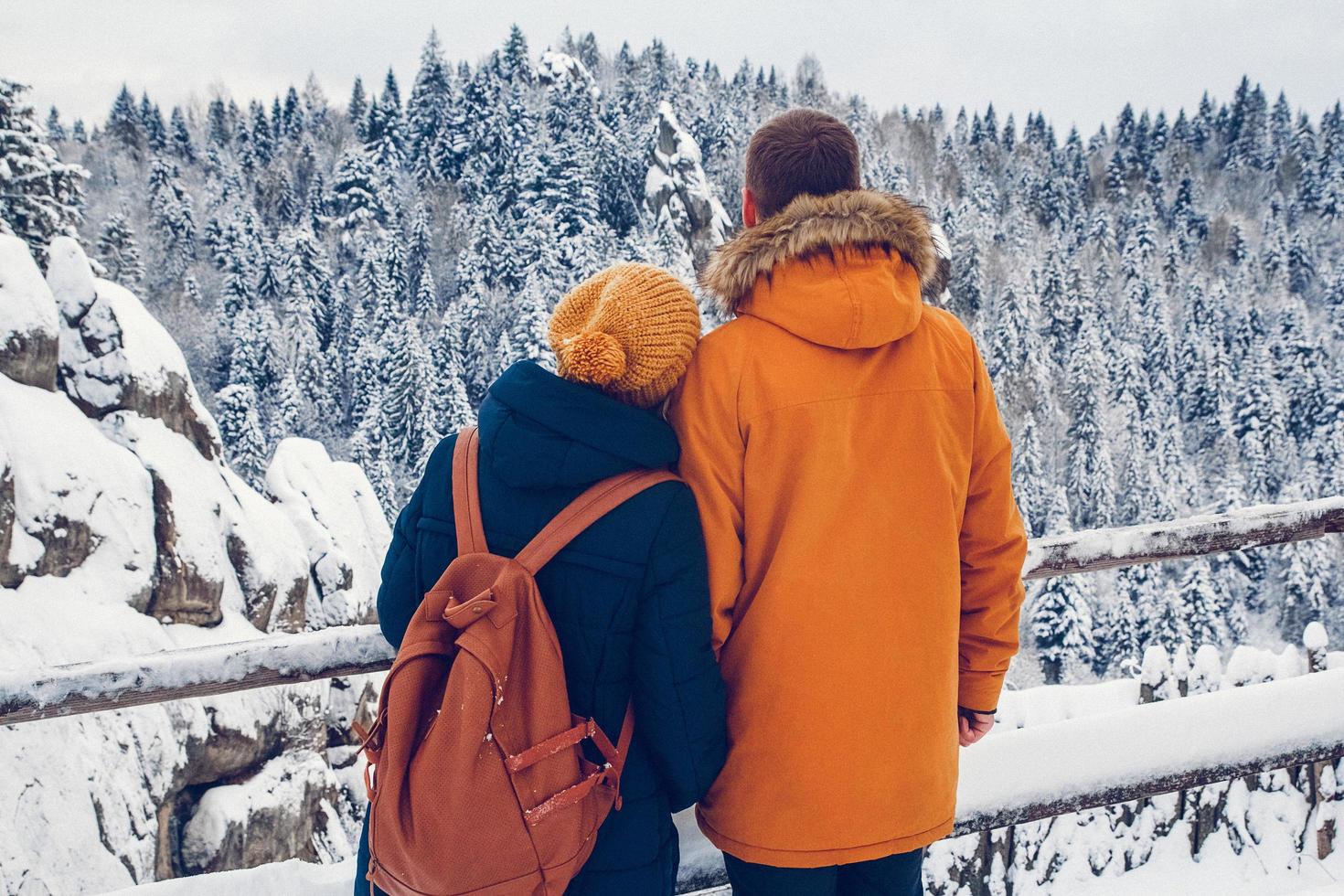 Pareja con mochilas disfrutando de vistas a la montaña durante las vacaciones de invierno foto