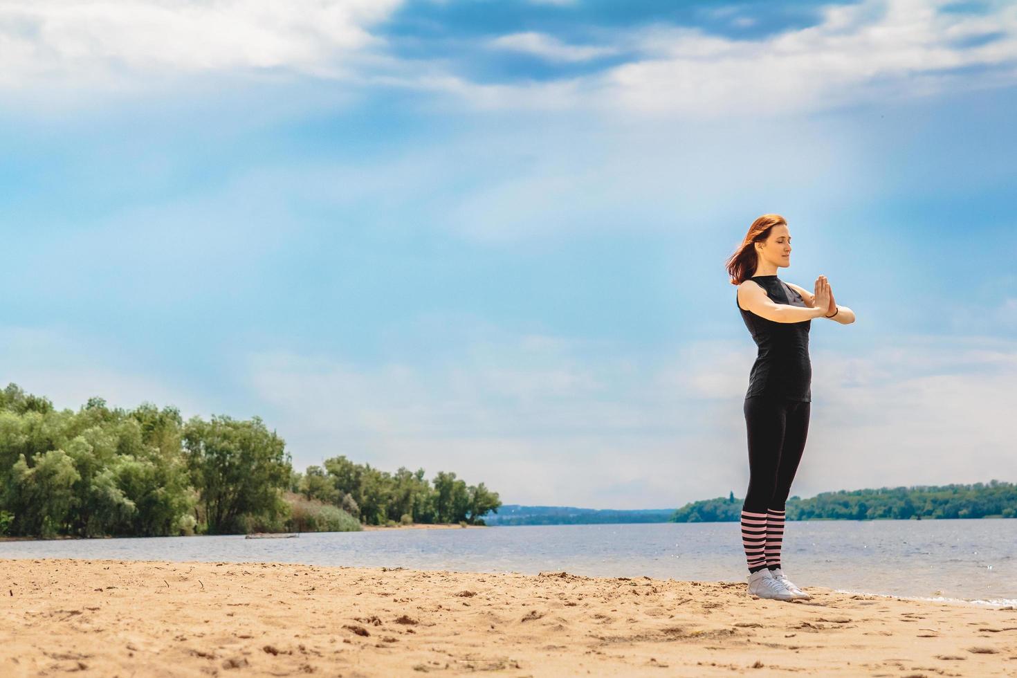mujer haciendo yoga en una playa de arena foto