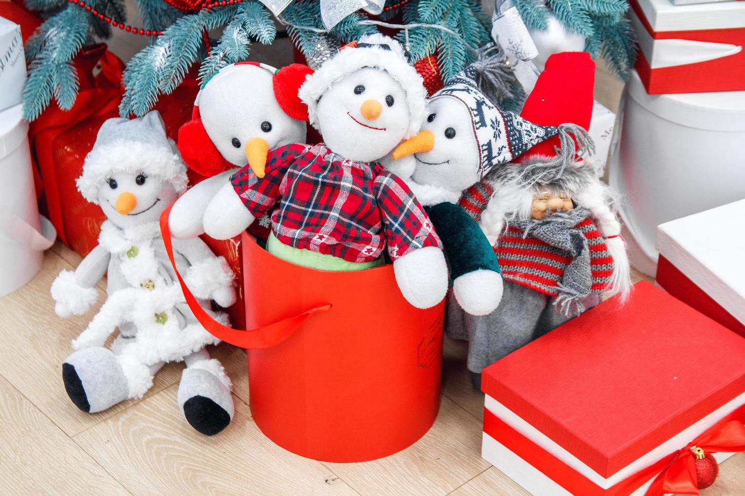 Funny toy snowmen and presents under decorated fir tree photo