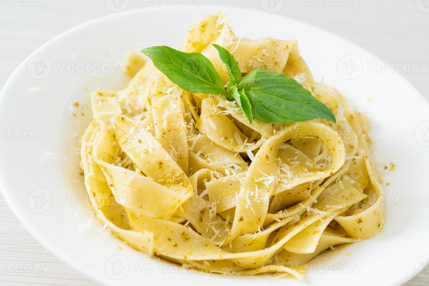 Pasta fettuccine al pesto con queso parmesano encima - estilo de comida italiana foto