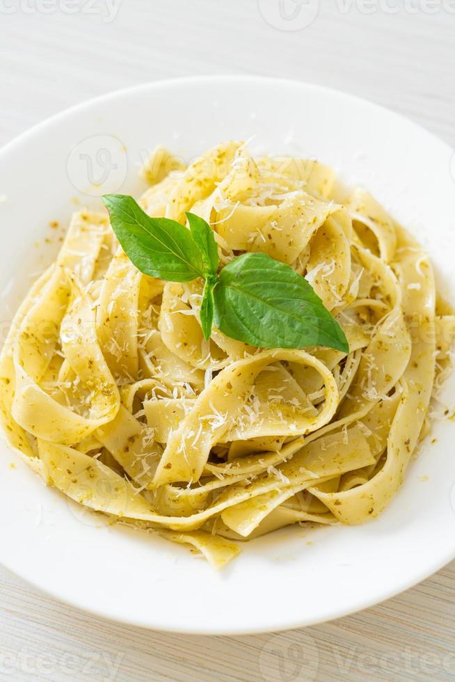 Pesto fettuccine pasta with parmesan cheese on top - Italian food style photo