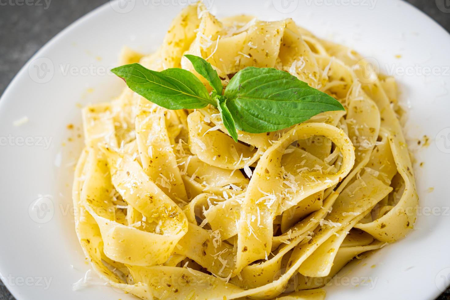 Pasta fettuccine al pesto con queso parmesano encima - estilo de comida italiana foto