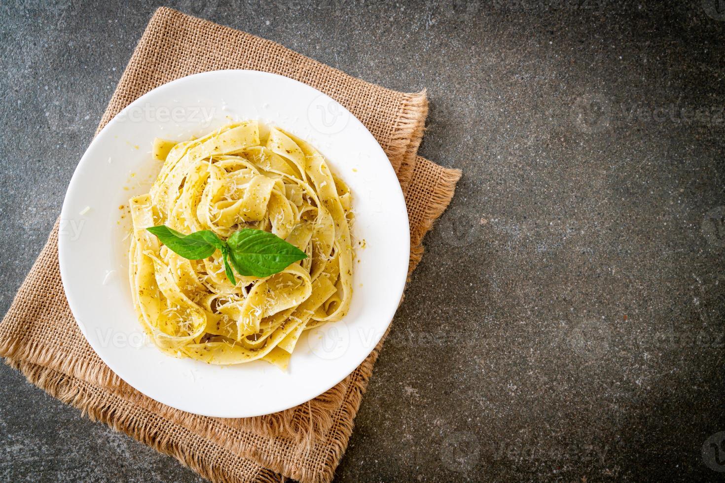 Pesto fettuccine pasta with parmesan cheese on top - Italian food style photo