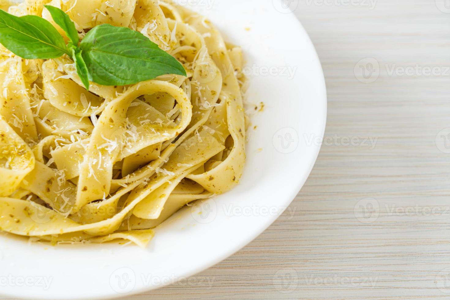 Pasta fettuccine al pesto con queso parmesano encima - estilo de comida italiana foto