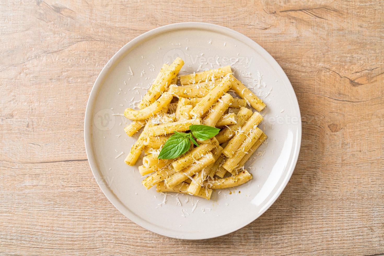 pasta al pesto rigatoni con queso parmesano - comida italiana y estilo vegetariano foto