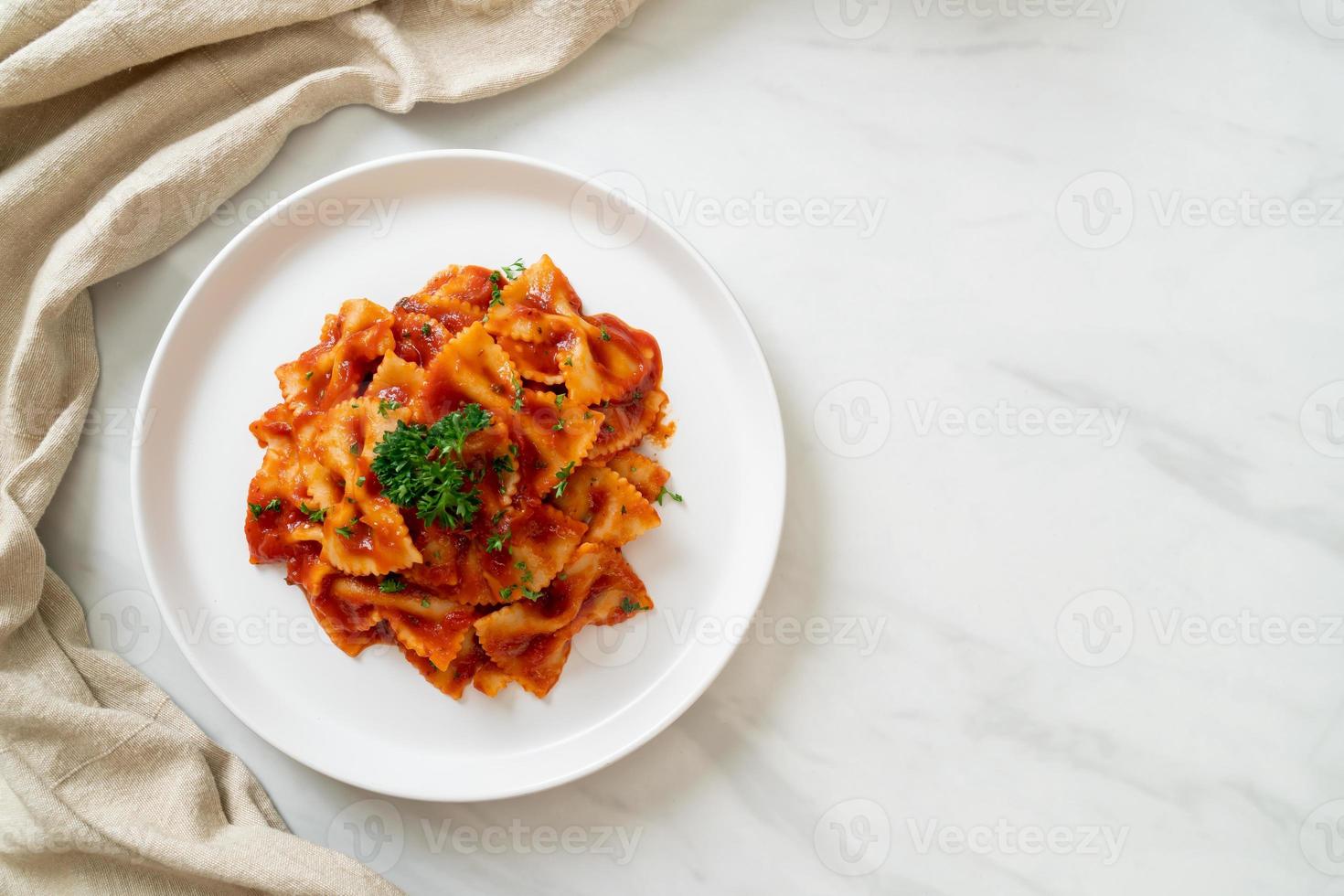 Pasta farfalle en salsa de tomate con perejil - estilo de comida italiana foto