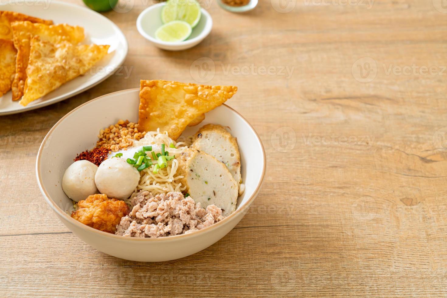 Fideos de huevo picantes con bolas de pescado y bolas de camarones sin sopa - estilo de comida asiática foto