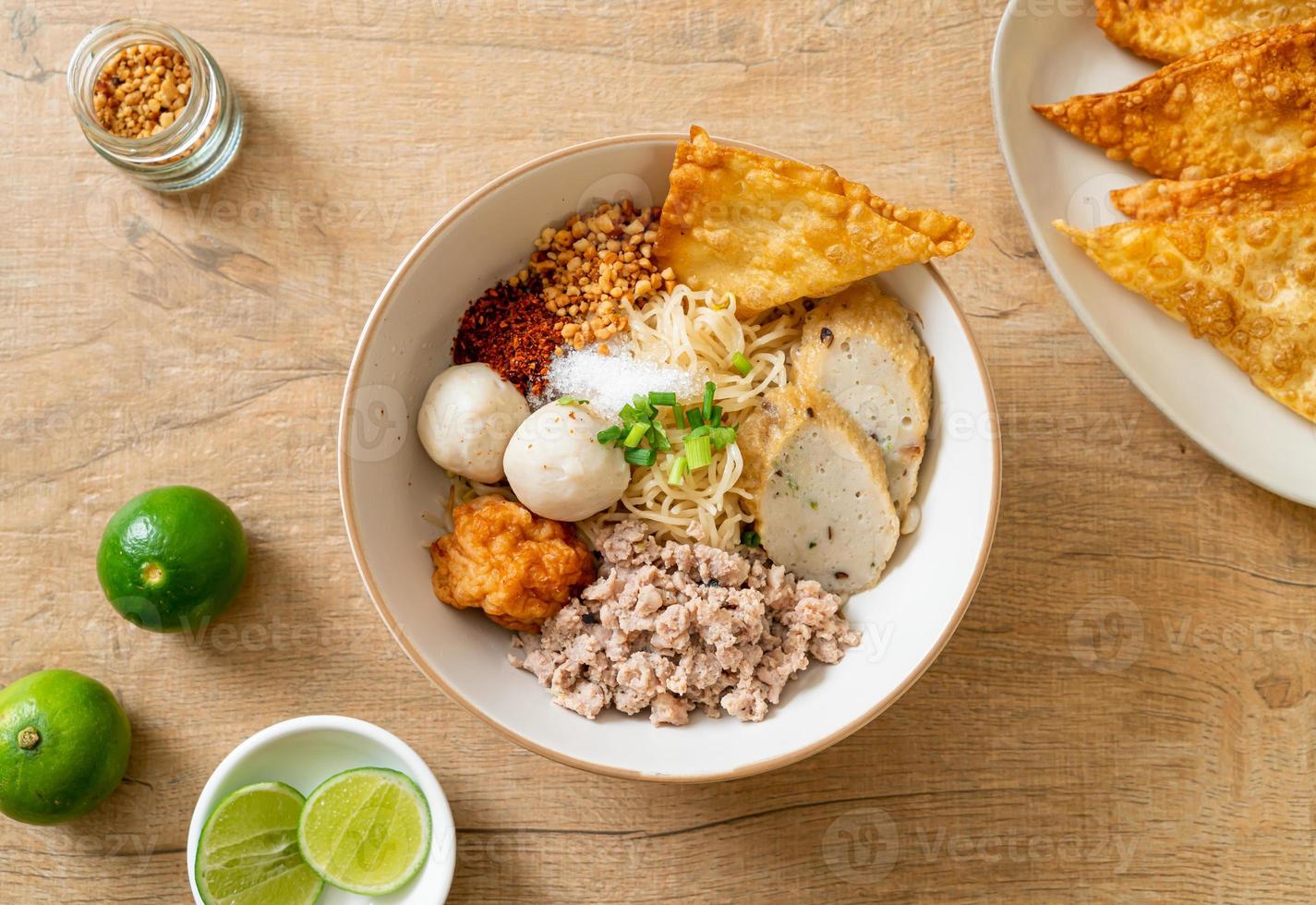 Fideos de huevo picantes con bolas de pescado y bolas de camarones sin sopa - estilo de comida asiática foto