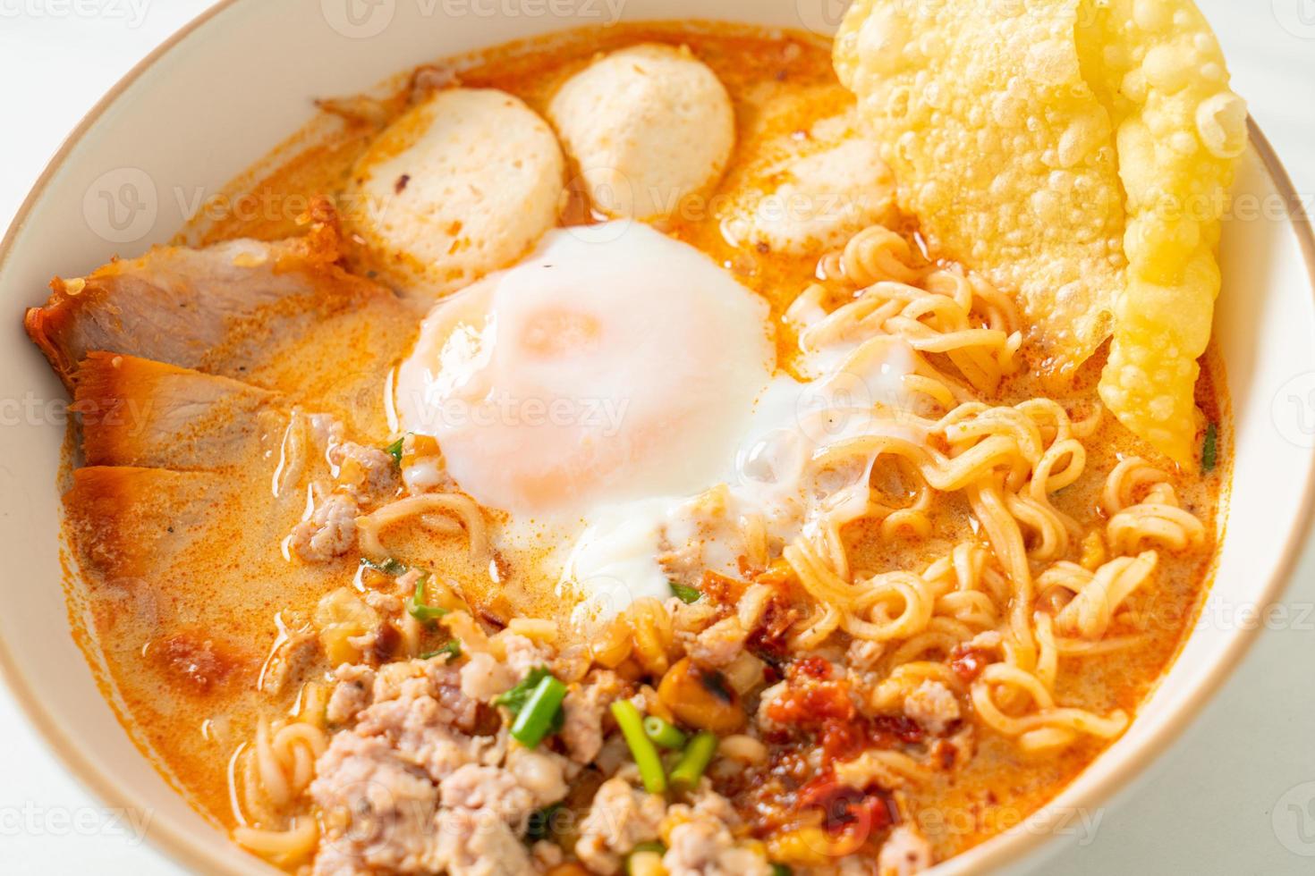 fideos instantáneos con carne de cerdo y albóndigas en sopa picante o fideos tom yum al estilo asiático foto