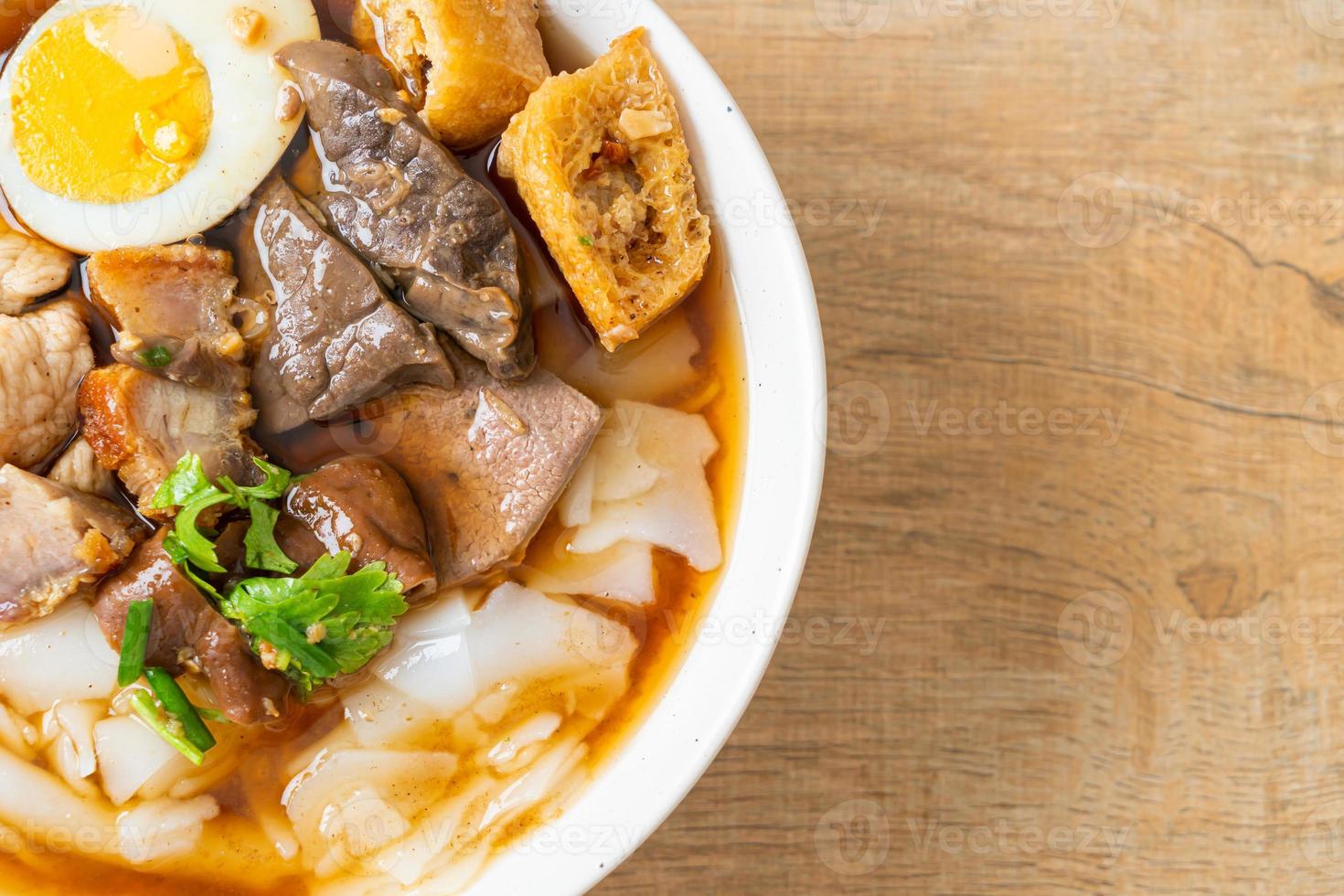 Pasta de harina de arroz o cuadrado de pasta china hervida con carne de cerdo en sopa marrón - estilo de comida asiática foto