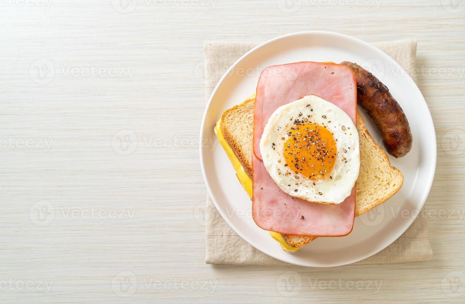 Pan casero con queso tostado, jamón y huevo frito con salchicha de cerdo y café para el desayuno. foto