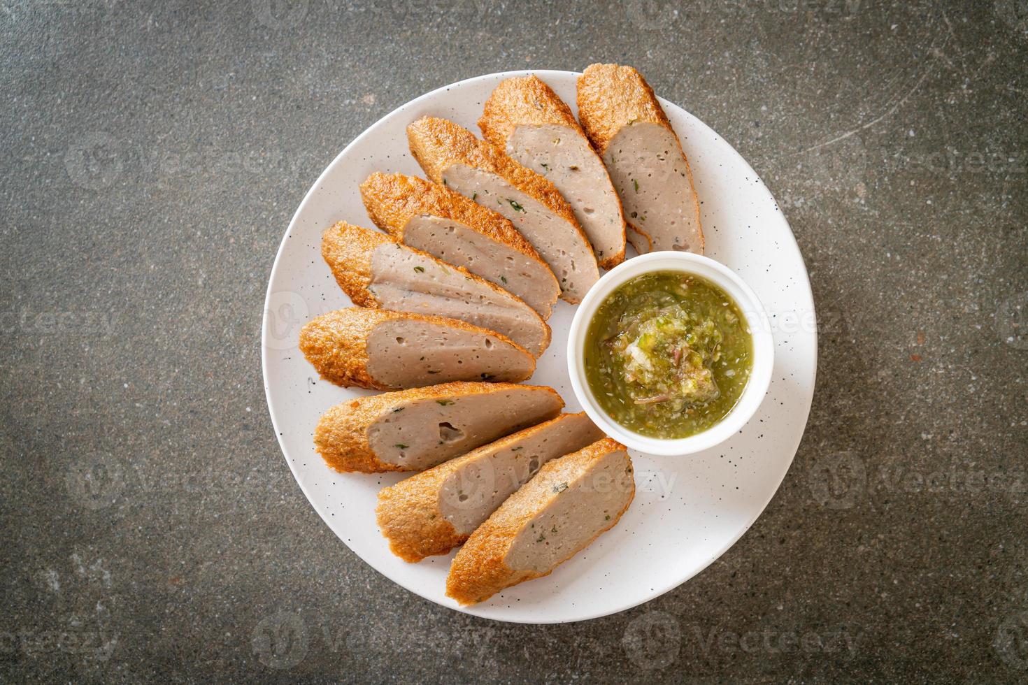 Fried Chinese fish cake or fish ball line sliced with spicy seafood dipping sauce photo