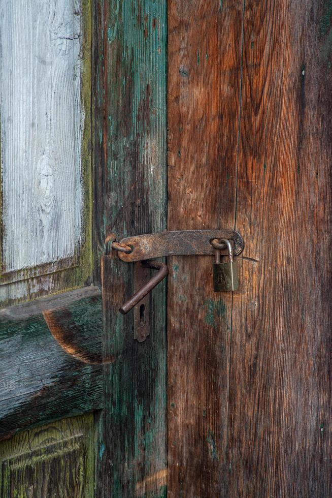 Disparo vertical de una cerradura oxidada en una antigua puerta de madera foto