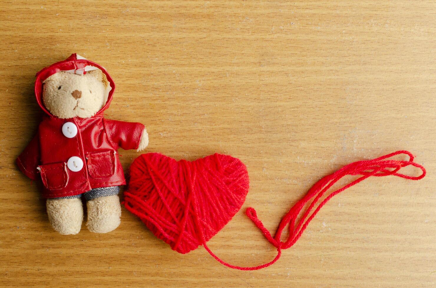 Oso de peluche con corazón rojo sobre fondos de madera para el día de San Valentín foto