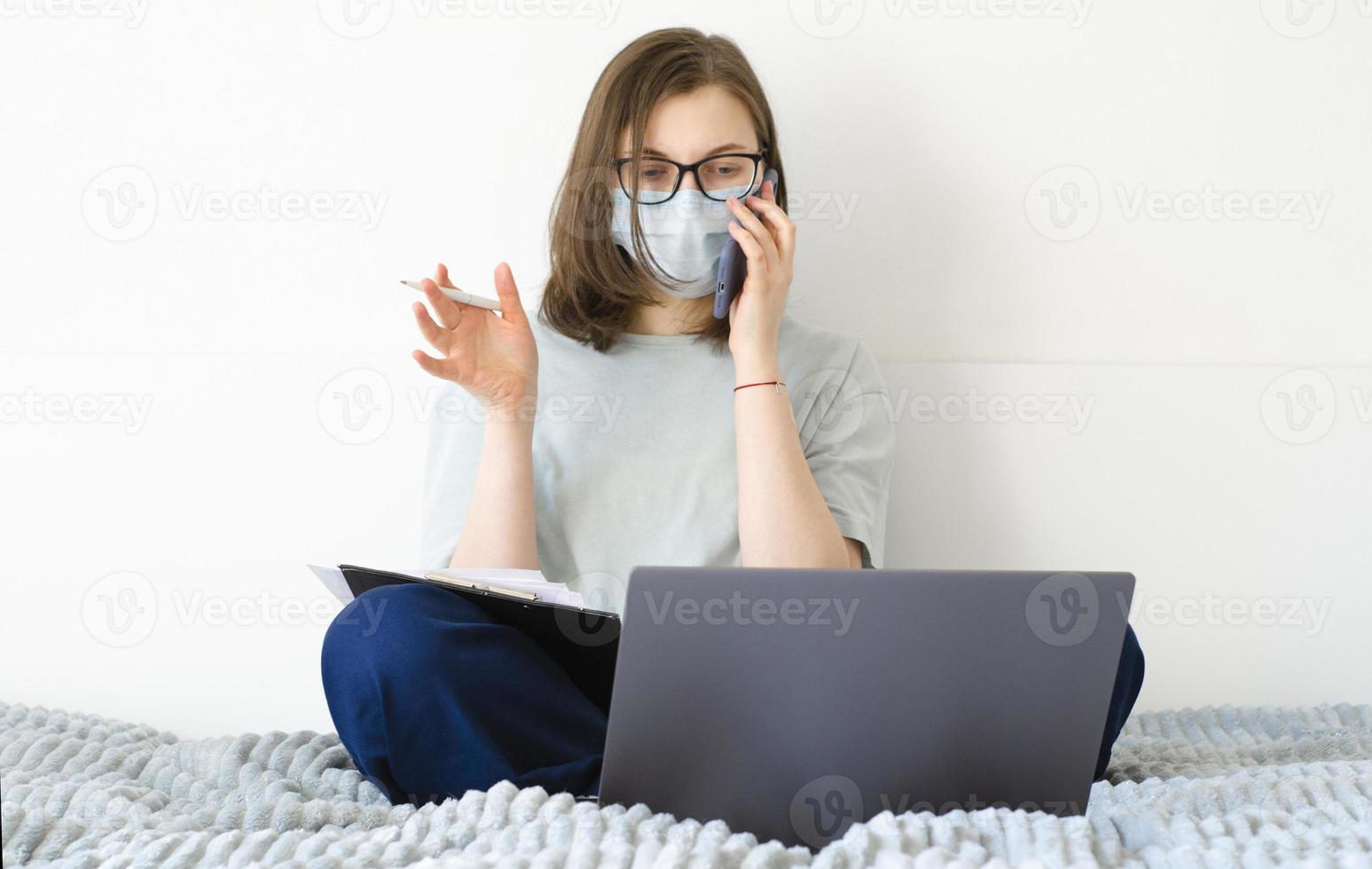 Girl in glasses and a mask. Solves work issues, signs documents. photo