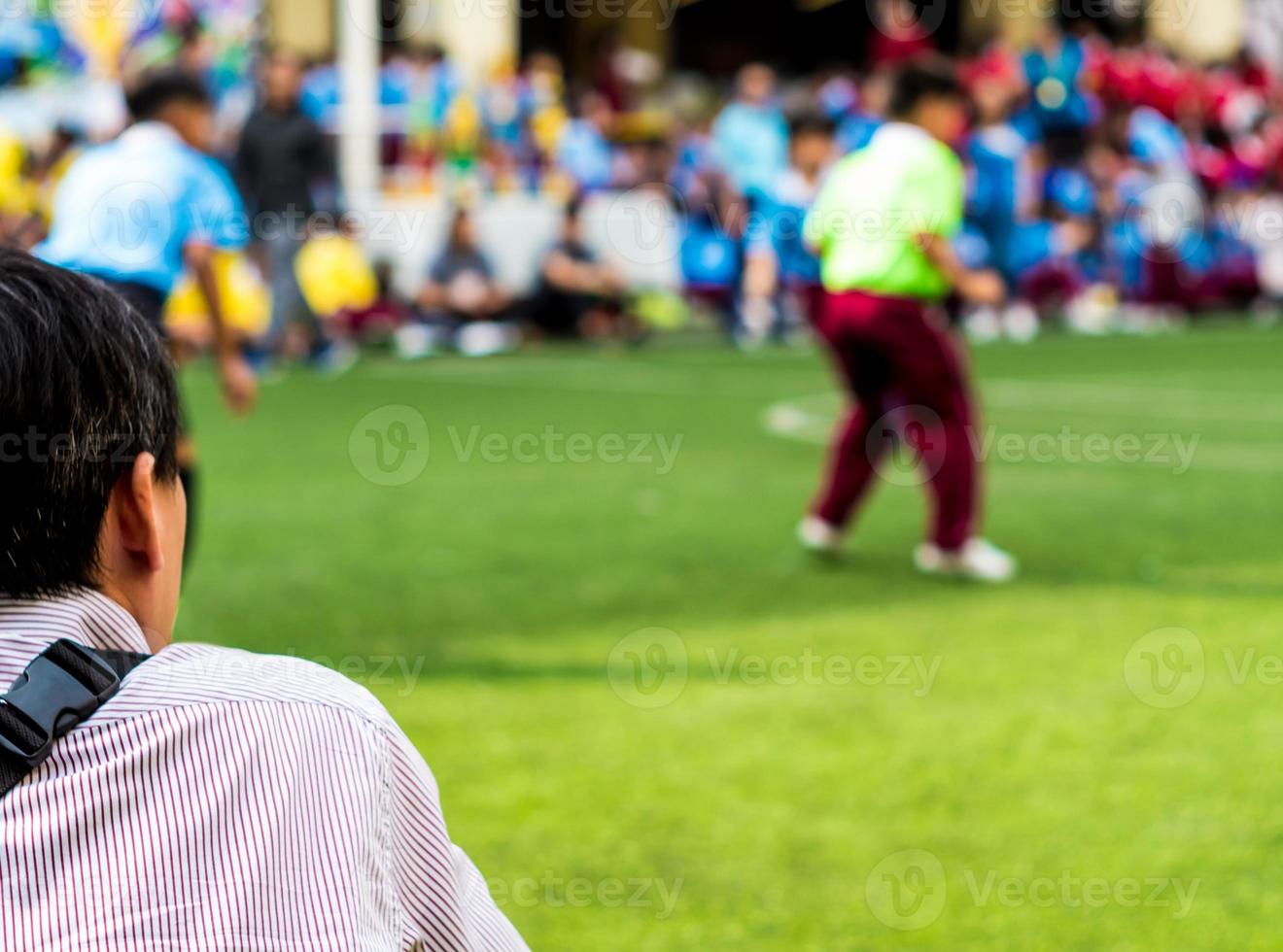 un hombre mira las competiciones de fútbol al lado del campo de fútbol foto