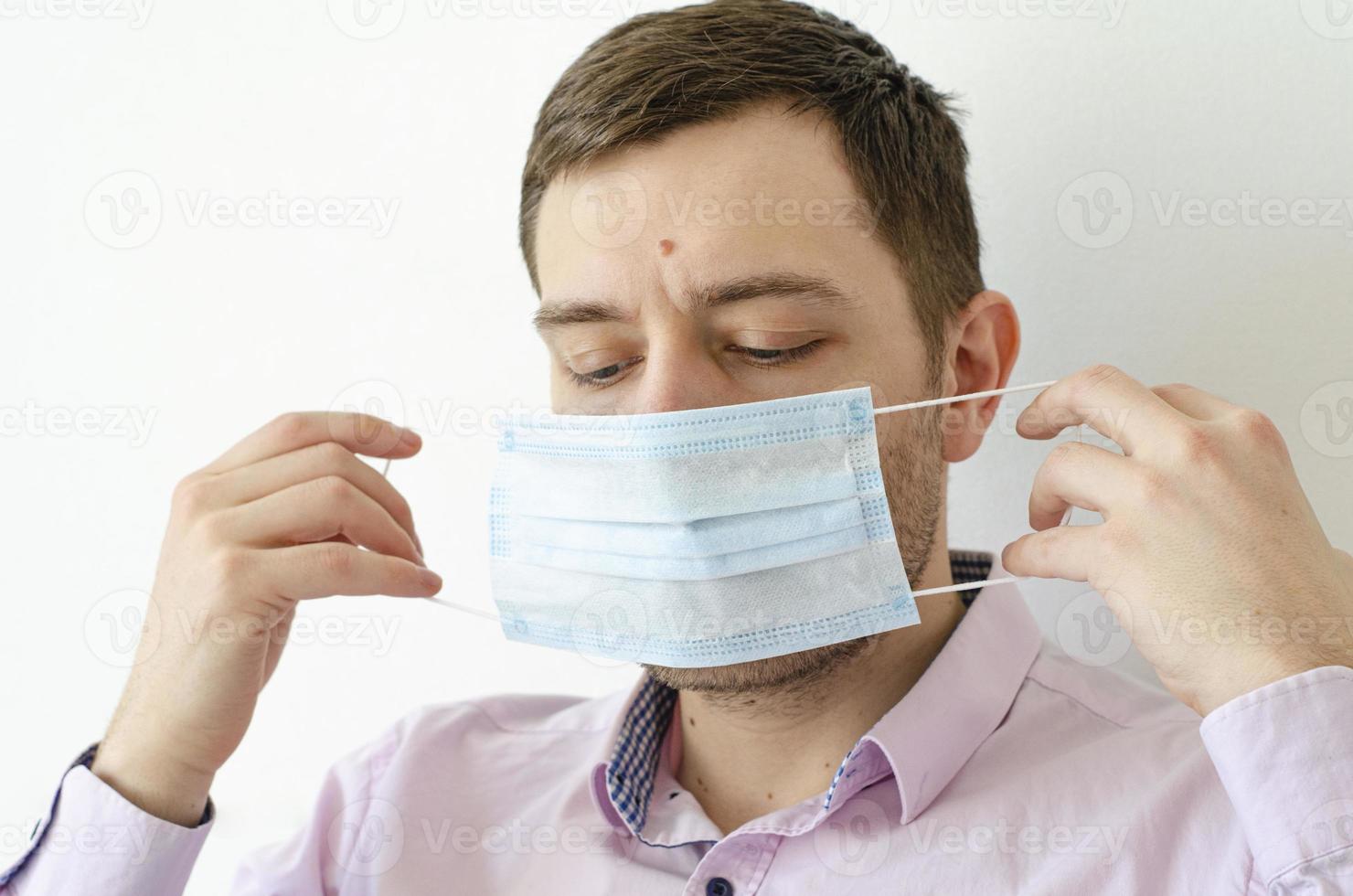 A man in a shirt puts on a mask. Virus protection. photo