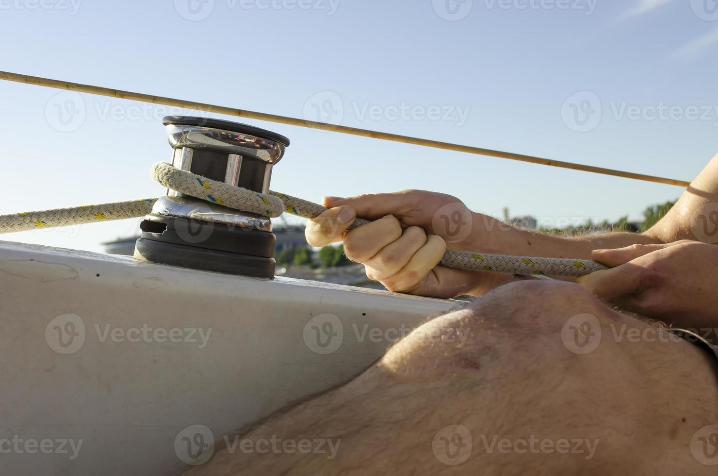 Handsome man working on sailboat. Water sport. photo