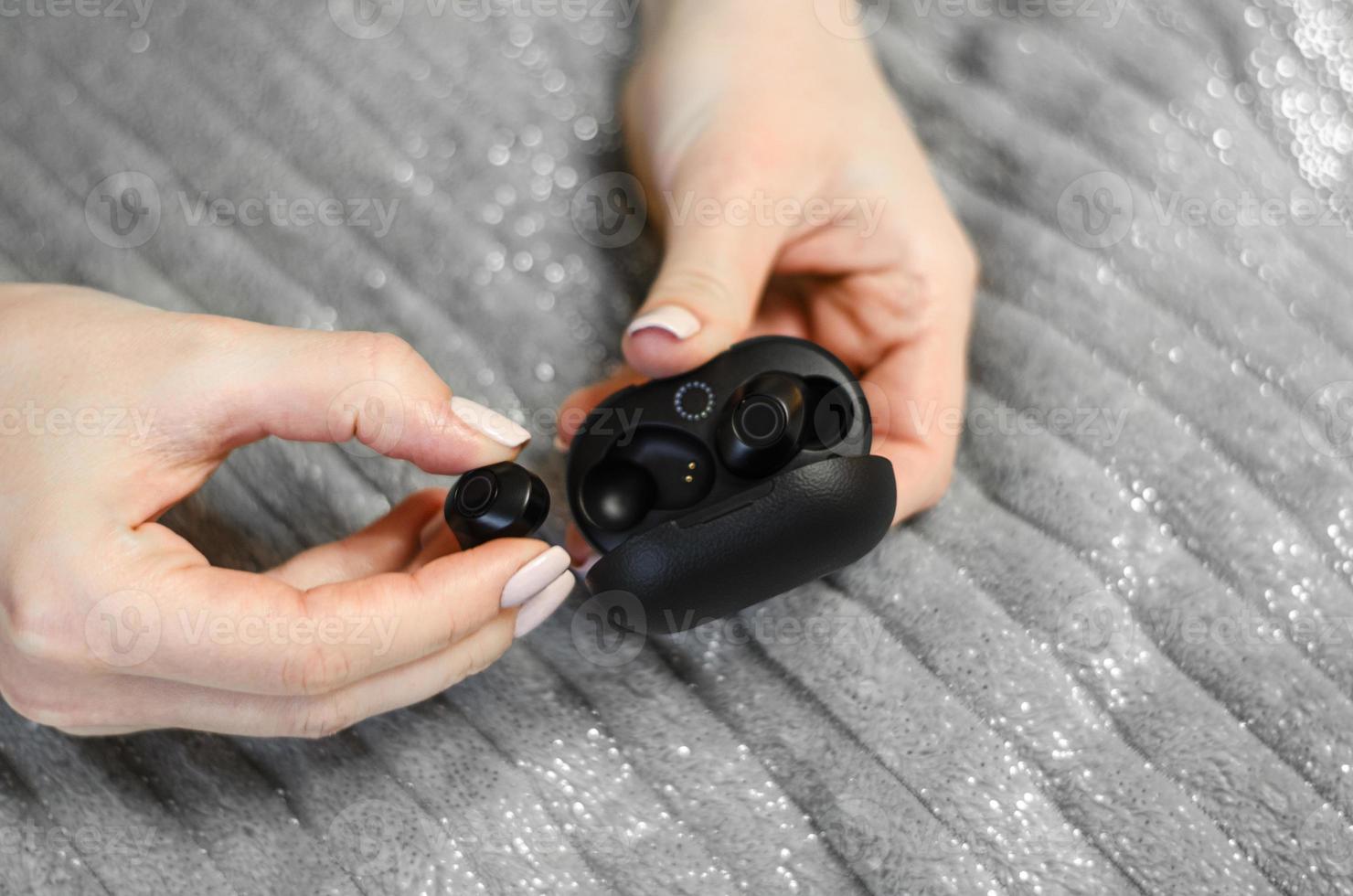 A girl takes out wireless headphones from a case. photo