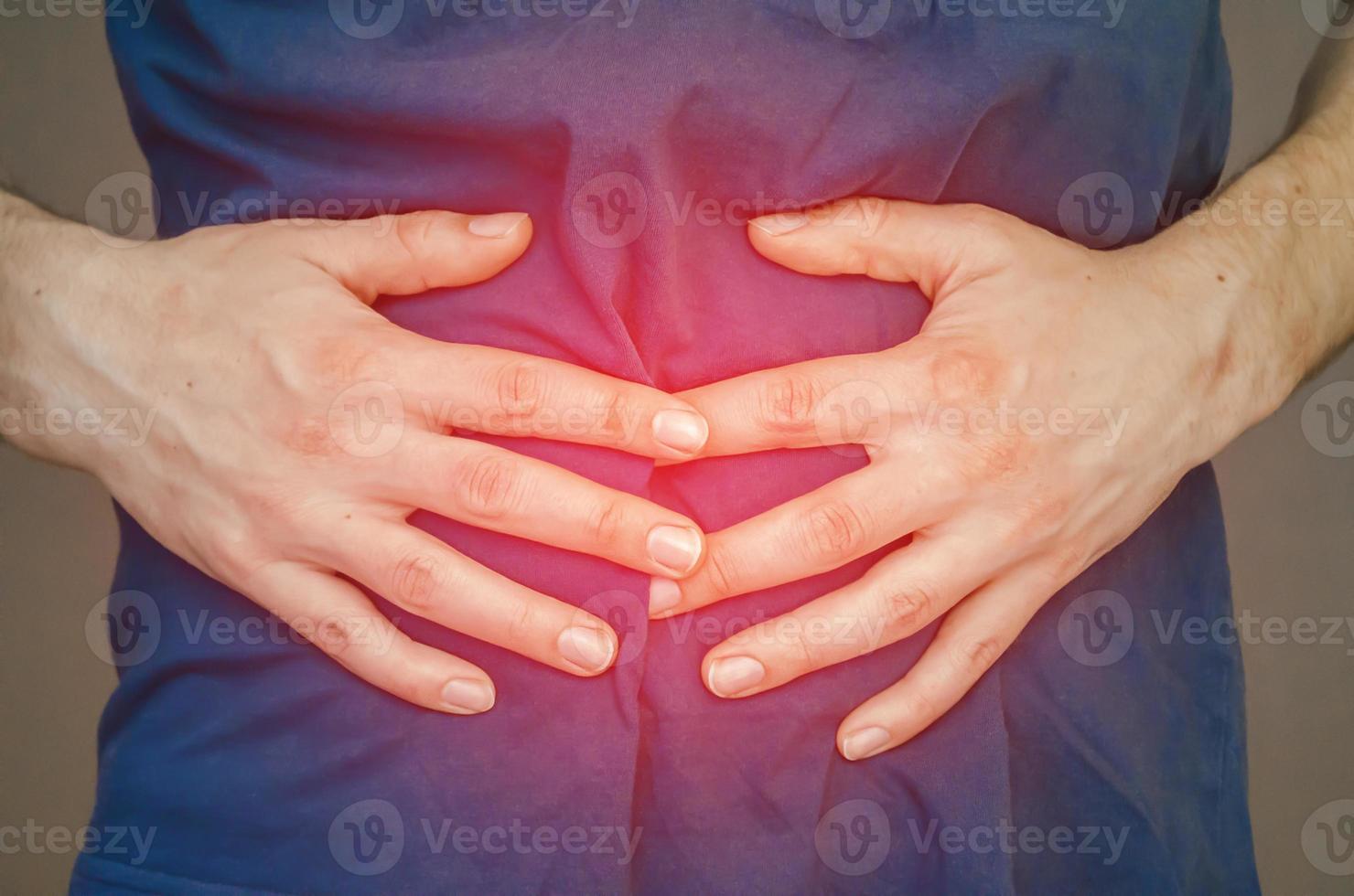 A man holding his stomach. Close up. photo